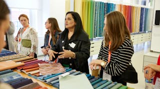 Visitors to this NeoCon showroom examine textiles. The 2023 show embodied its theme, &ldquo;Together We Design.&rdquo;