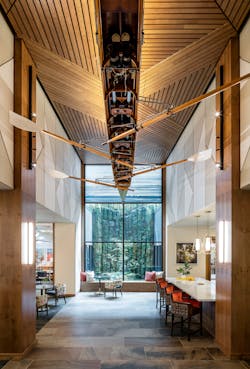 A large rowing boat is suspended from the ceiling in the hall, with the above wood ceiling matching the herringbone pattern. The d&eacute;cor and color were inspired by the local rowing history.