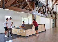 New concierge desk consolidates mail and package delivery. The desk is clad in salvaged maple gym flooring. The backlit decorative pattern is an abstraction of basketball play diagrams.