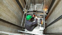 A machinist repairs an elevator in its shaft. A machinist repairs an elevator in its shaft.