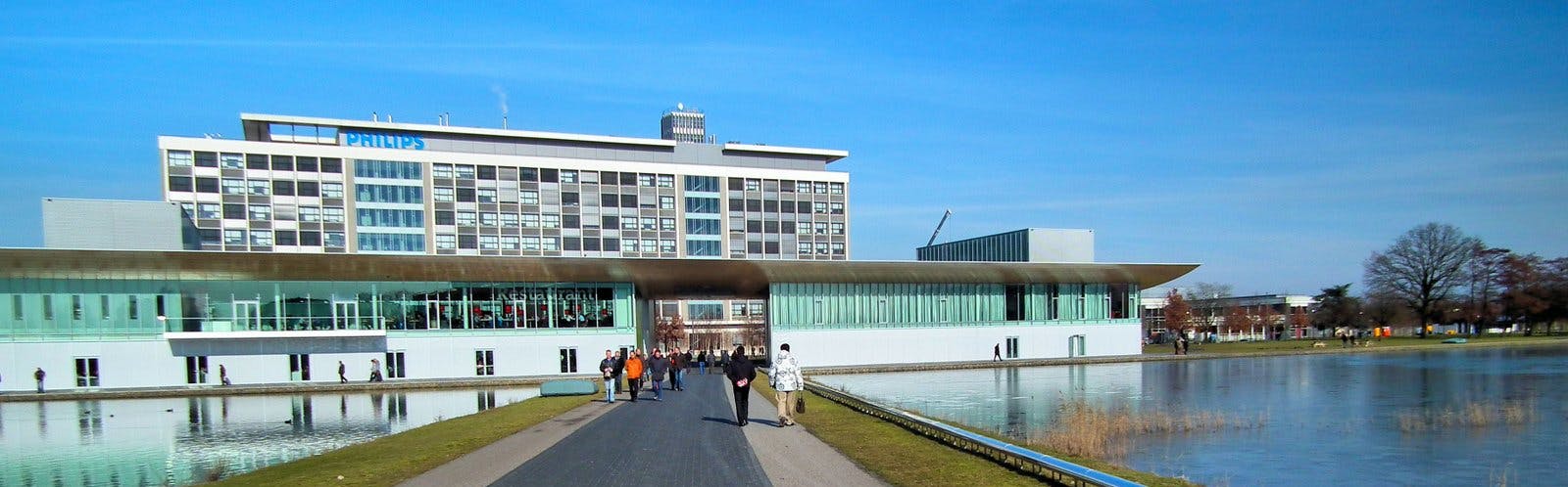 Signify's headquarters are located at Eindhoven's High Tech Campus, a site established in 1998 by former Signify owner Philips, which still houses its innovation group there, and which is home to other technology and research groups as well. Signify will soon provide details on its cutbacks there. (Photo credit: File photo courtesy of Microtoerisme via Wikimedia Commons; used under CC BY-SA 3.0 - http://bit.ly/3piOJep.)