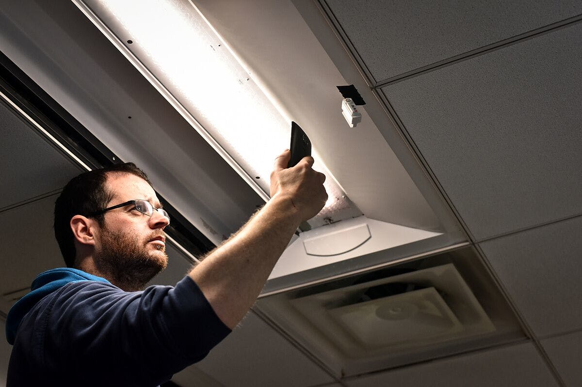 An installer uses a cell phone to configure a connected lighting system in a Next Generation Lighting Systems (NGLS) living lab. [Photo credit: Image courtesy of Pacific Northwest National Laboratory (PNNL) and NGLS.]