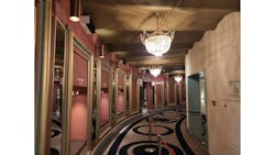 Amsterdam's Royal Theater Carré installed some of the 75 upper-air UV-C disinfection luminaires in this corridor. They are the black-and-white rectangular boxes at the top of the pink wall along the left. (Photo credit: Image courtesy of Signify.) Amsterdam's Royal Theater Carré installed some of the 75 upper-air UV-C disinfection luminaires in this corridor. They are the black-and-white rectangular boxes at the top of the pink wall along the left. (Photo credit: Image courtesy of Signify.)