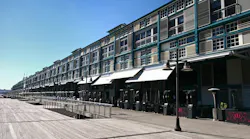 An adaptive reuse of a historic industrial wharf building at Finger Wharf, Woolloomooloo in Sydney, Australia. The heritage timber structure, featuring a green frame, white shutters, and louvers, has been transformed into the Ovolo Hotel, restaurants, and residential apartments, blending history with modern waterfront living.