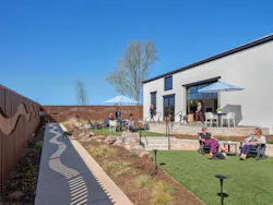 The outside had to accommodate both dogs and their owners, meaning a grade change was transformed into a terraced seating area with a fence, various seating options, and native plants. A garage door creates a shared space between the indoor and outdoor multipurpose cafes for focus work and social gatherings alike.
