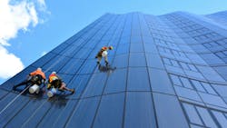 Window cleaners work on a high-rise building. Window cleaners work on a high-rise building.