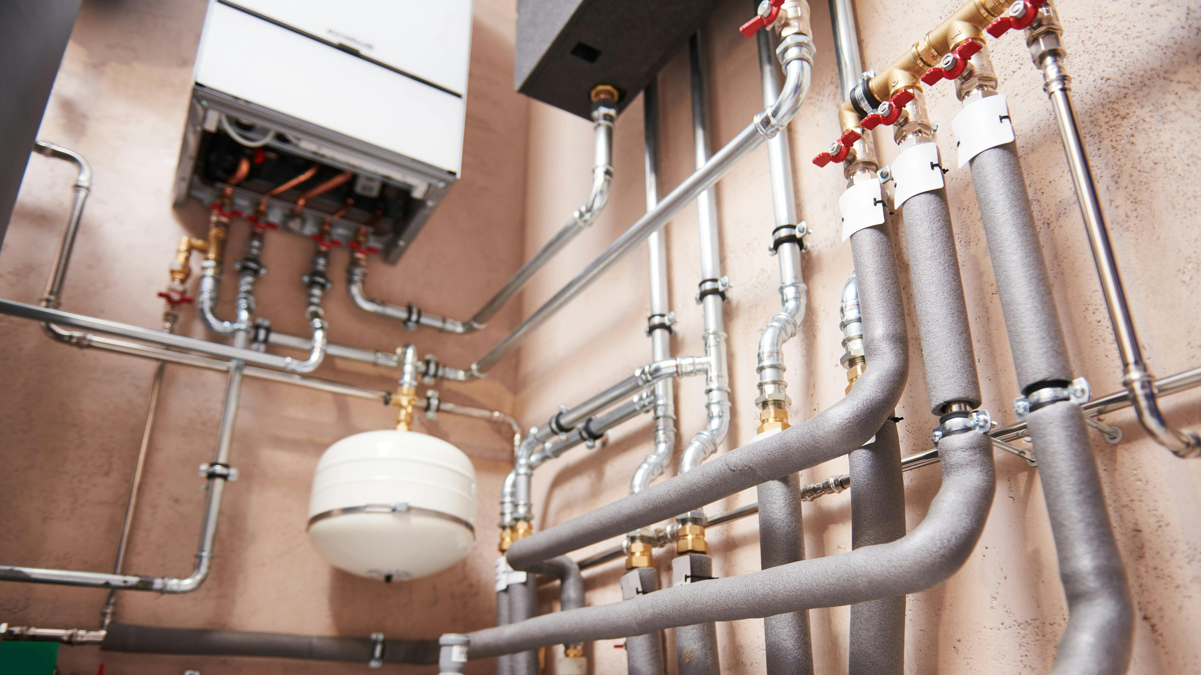 Hot water boiler room equipment with pipes mounted to wall.