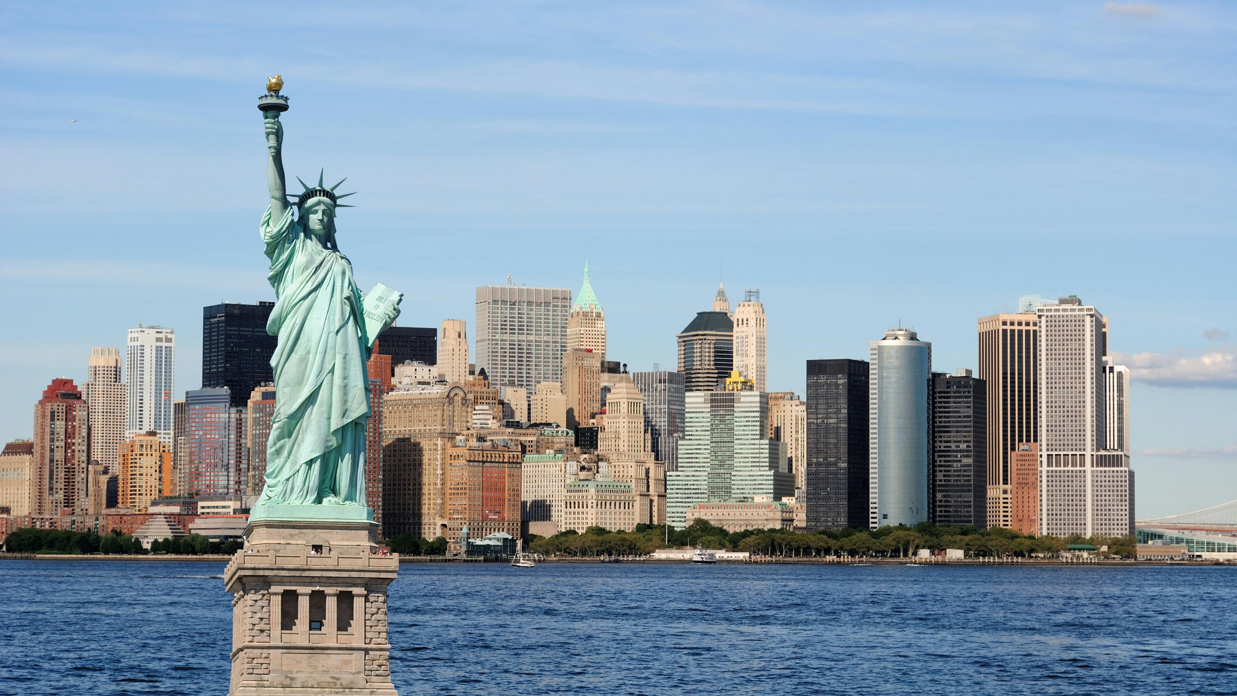 The Statue of Liberty stands against the New York City skyline.