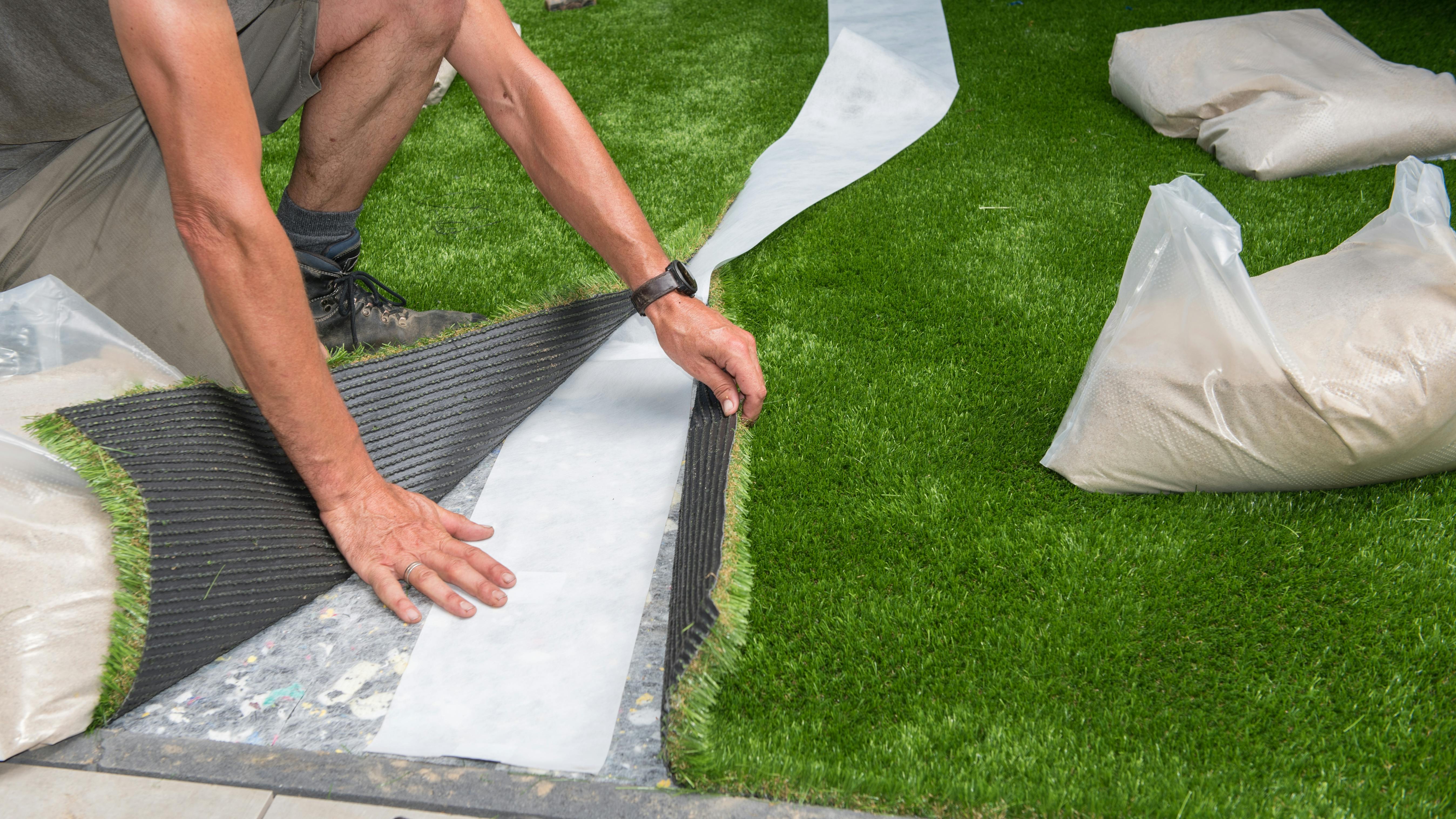 A professional gardener cuts artificial turf to fit.